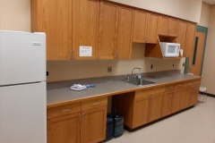 A picture of a prep kitchen with a sink, microwave, and fridge. 